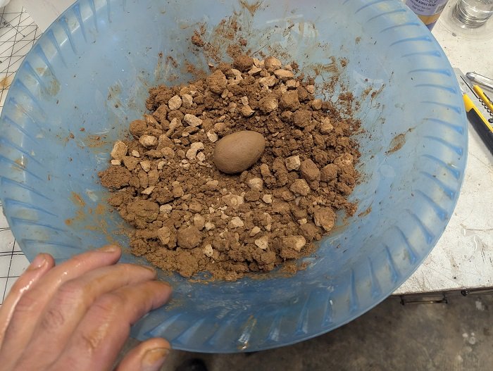 A bowl of bits of clay with a clay egg in the middle